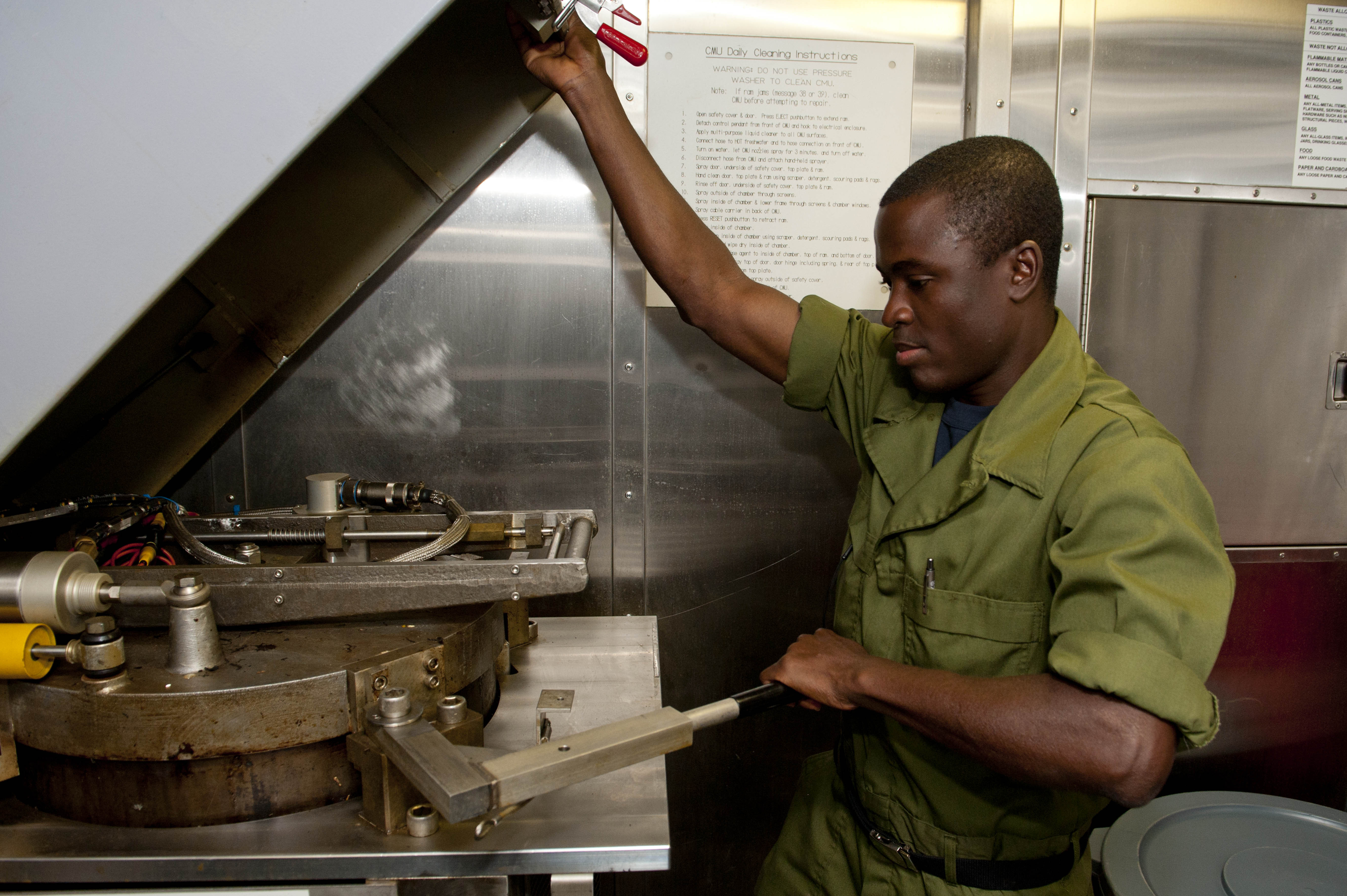 This is an image of a United States Navy Sailor operating a plastic waste processor machine.